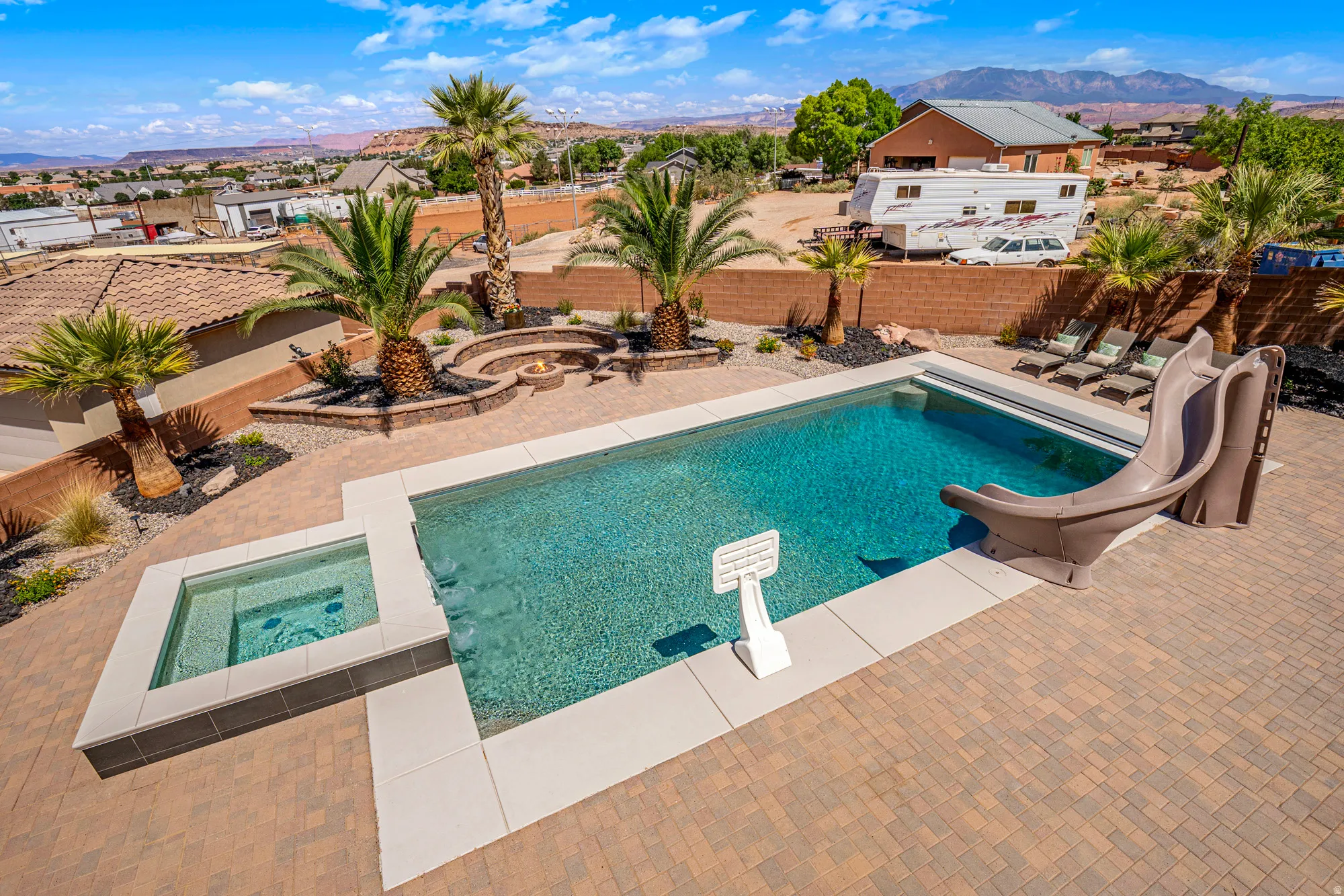Backyard oasis featuring a swimming pool with an integrated slide, an adjacent spa, and extensive paver patio