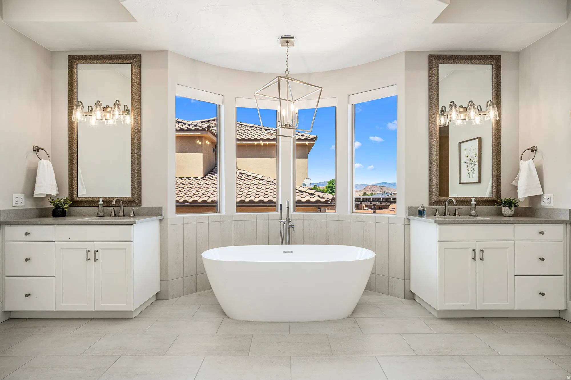 Freestanding soaking tub with a floor-mounted faucet, complemented by dual vanity cabinets with undermount sinks and light-toned countertops