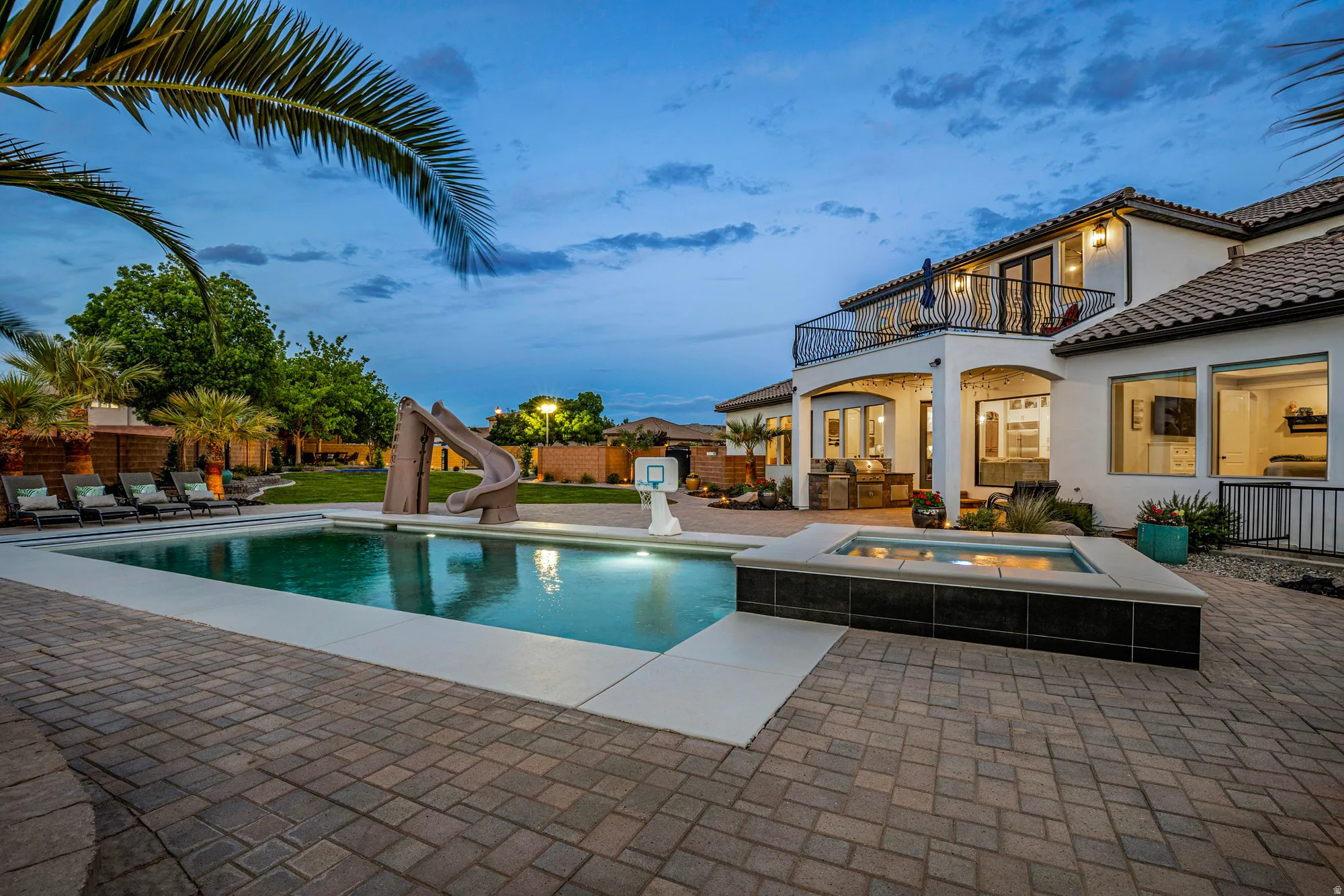 Expansive paver patio featuring a swimming pool, integrated spa, and a built-in outdoor kitchen