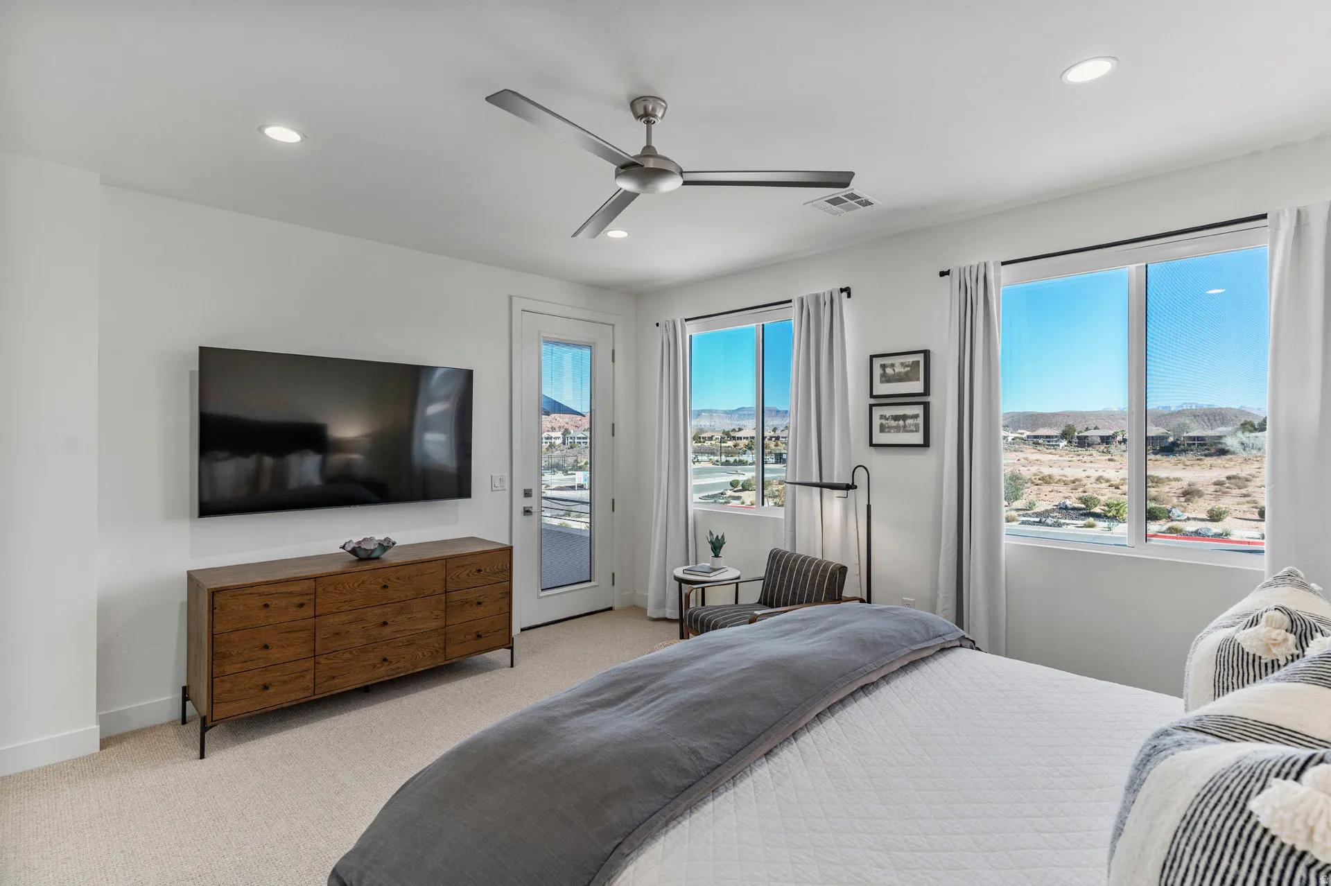 Well-lit primary bedroom featuring a ceiling fan, recessed lighting, and a wall-mounted television above a wood-finish dresser