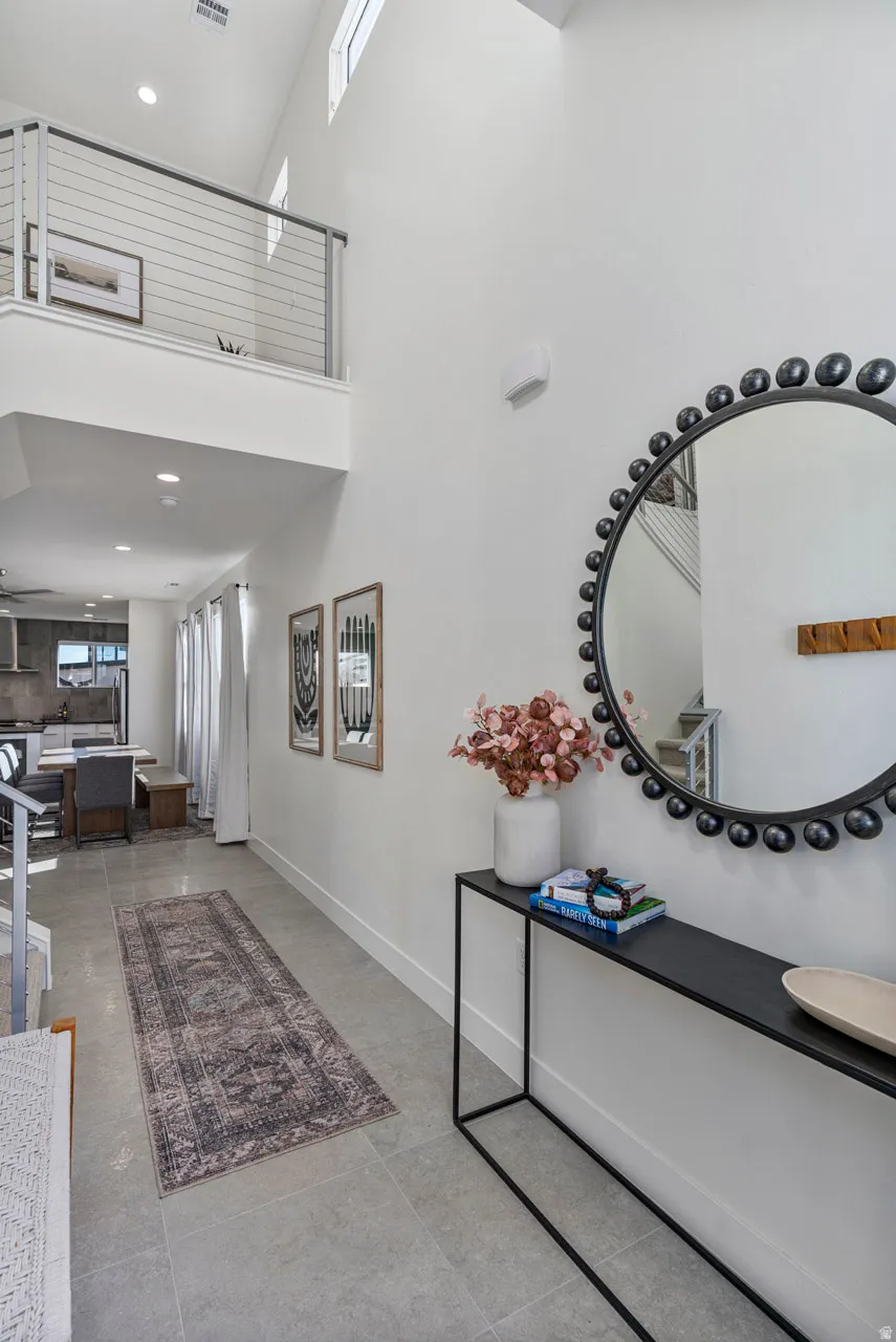 Entryway featuring a two-story ceiling, a second-story landing with cable railing, and high windows providing natural light