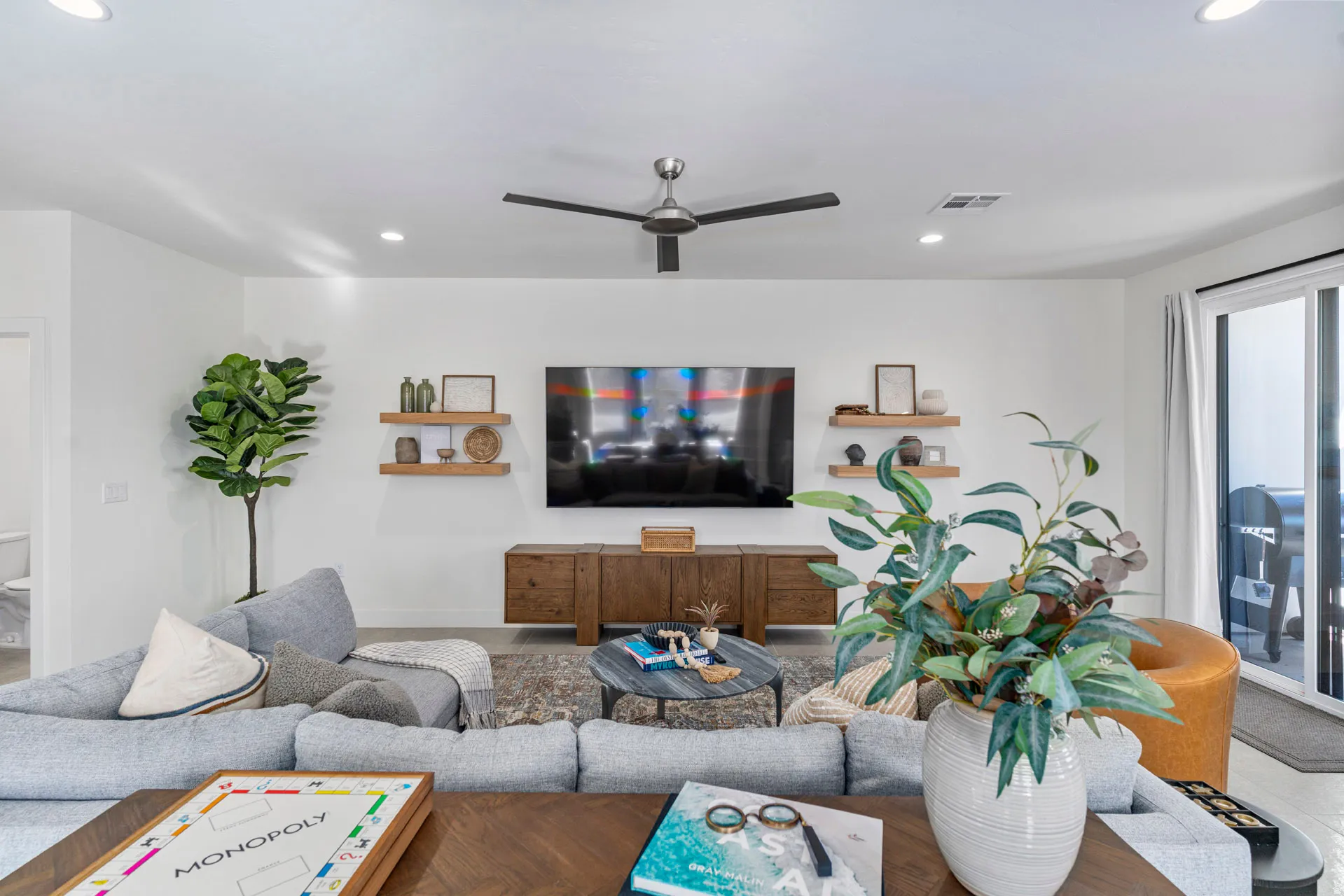 Living area featuring recessed lighting, a ceiling fan, wood-finish floating shelves, and a sliding glass door to exterior