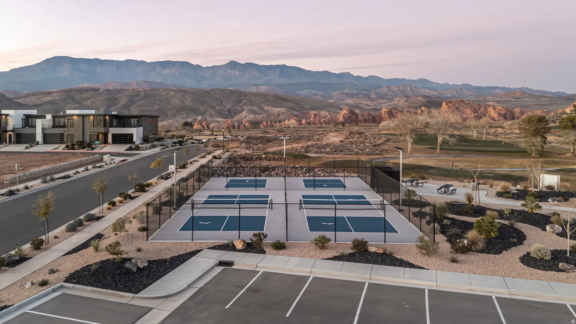 Four pickleball courts with perimeter fencing, surrounded by desert landscaping and framed by distant mountains