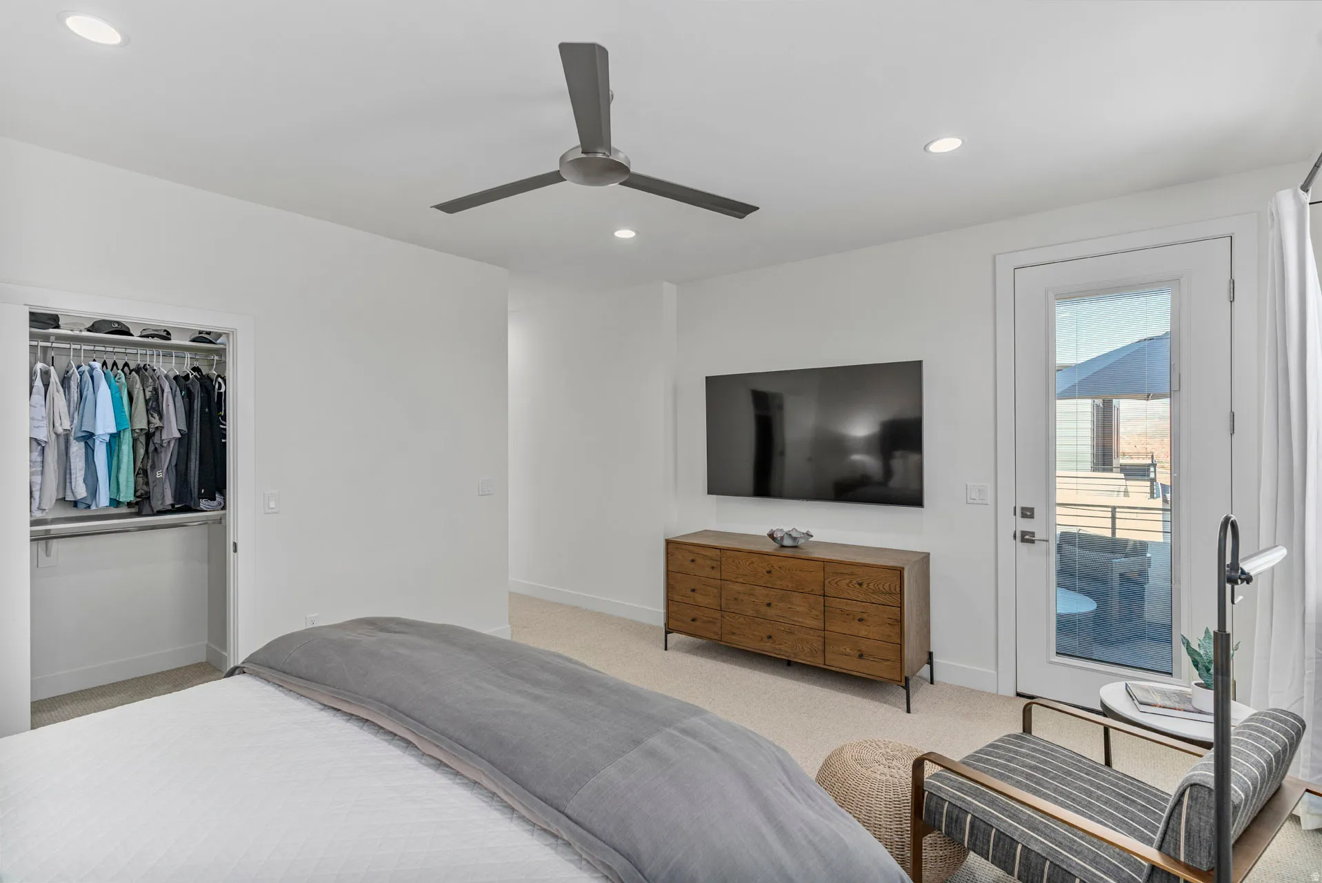 Primary bedroom with white walls and plush carpet flooring complement a ceiling fan and recessed lighting