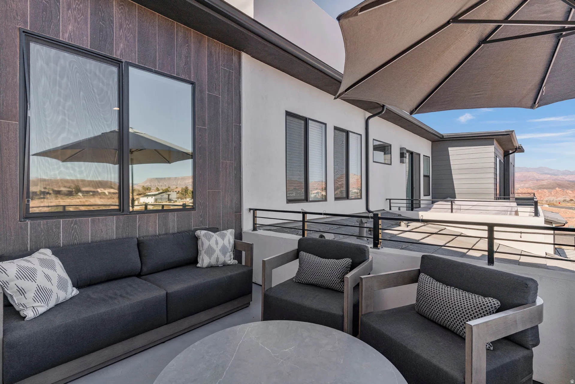 Primary bedroom spacious outdoor balcony featuring durable concrete flooring and dark wood-look paneling