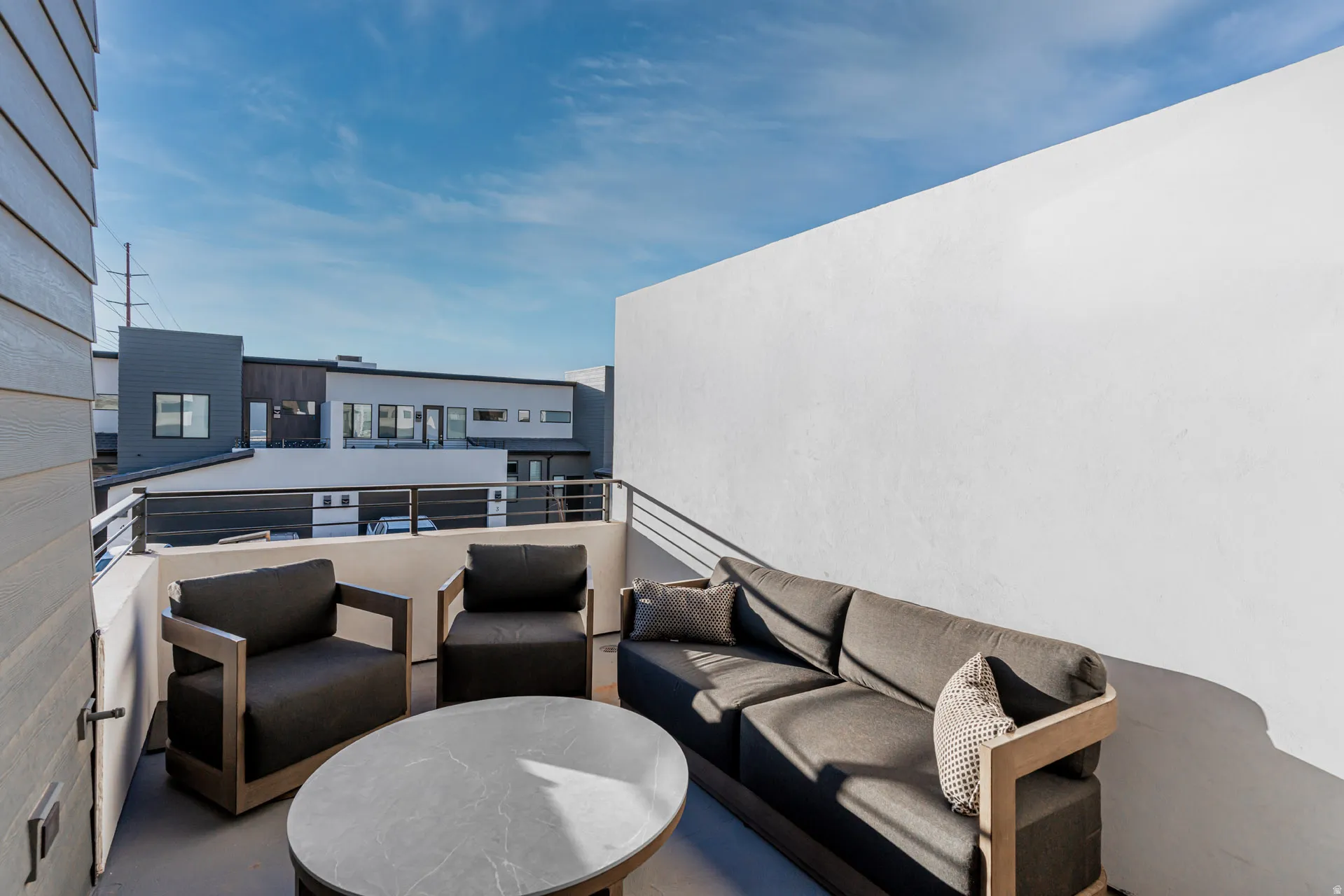 Front outdoor balcony featuring a stucco privacy wall, metal railing, and horizontal siding