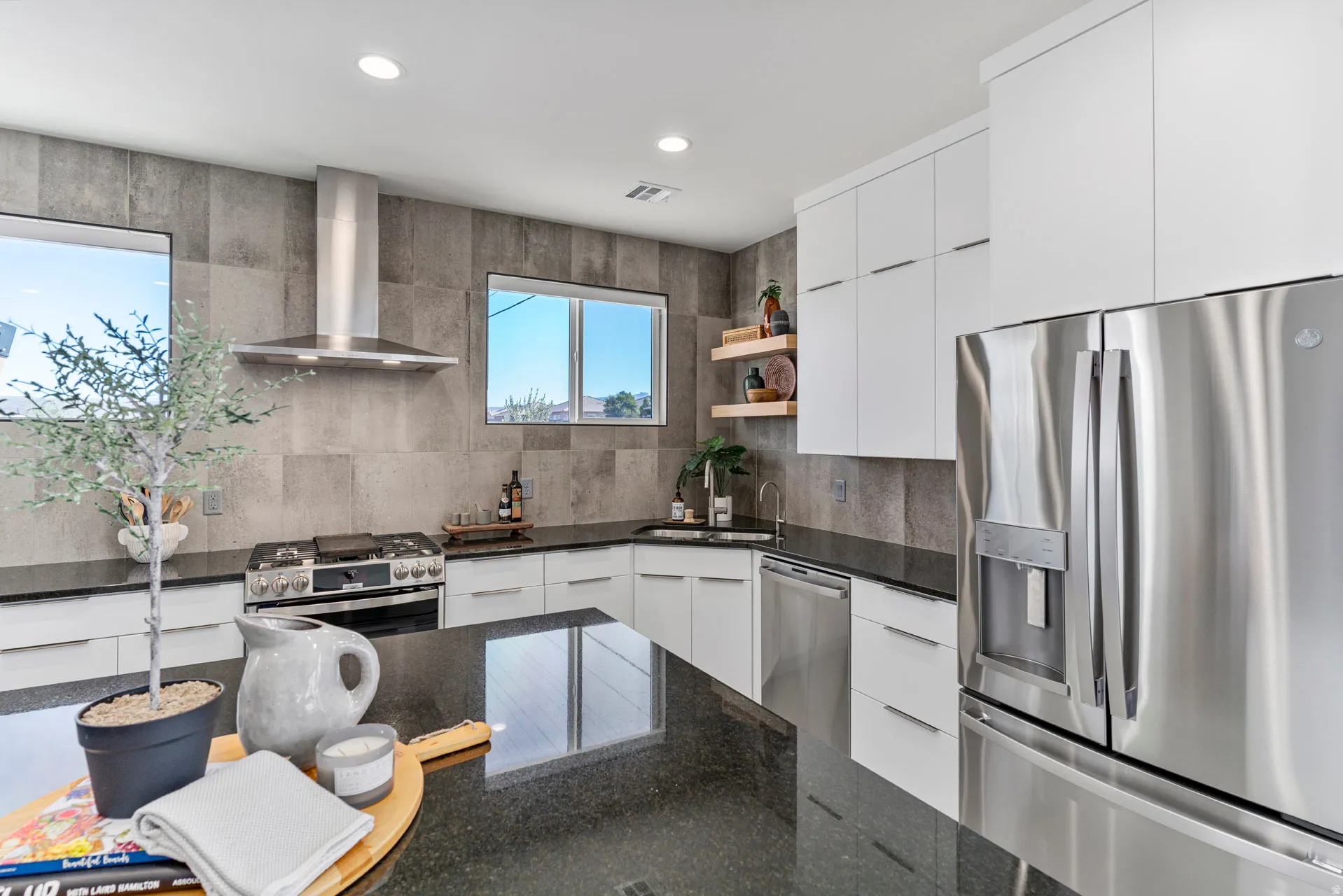 Modern kitchen featuring a stainless steel appliance suite, white cabinetry, dark countertops, and a gray tiled backsplash