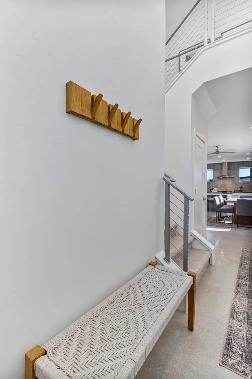 Open-concept entryway featuring a modern staircase with cable railings, expansive tile flooring, and a clear sightline into the kitchen with stainless steel appliances