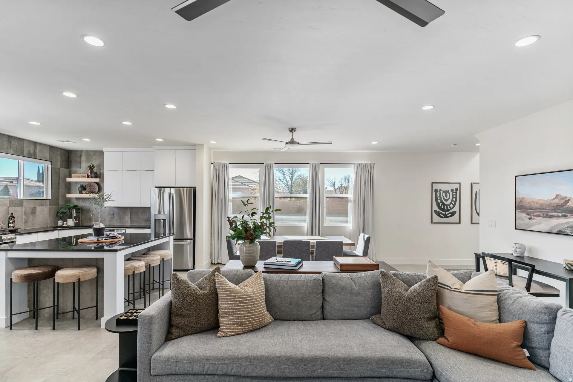 Open-concept living space featuring a spacious kitchen island with seating, stainless steel appliances, recessed lighting, and multiple windows