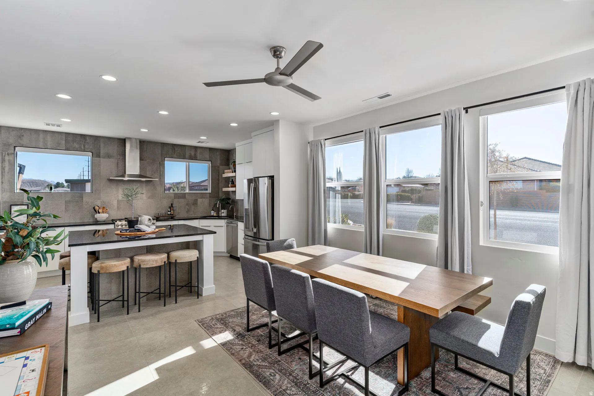Open-concept kitchen and dining area featuring a spacious island with seating, dark countertops, and a modern stainless steel range hood