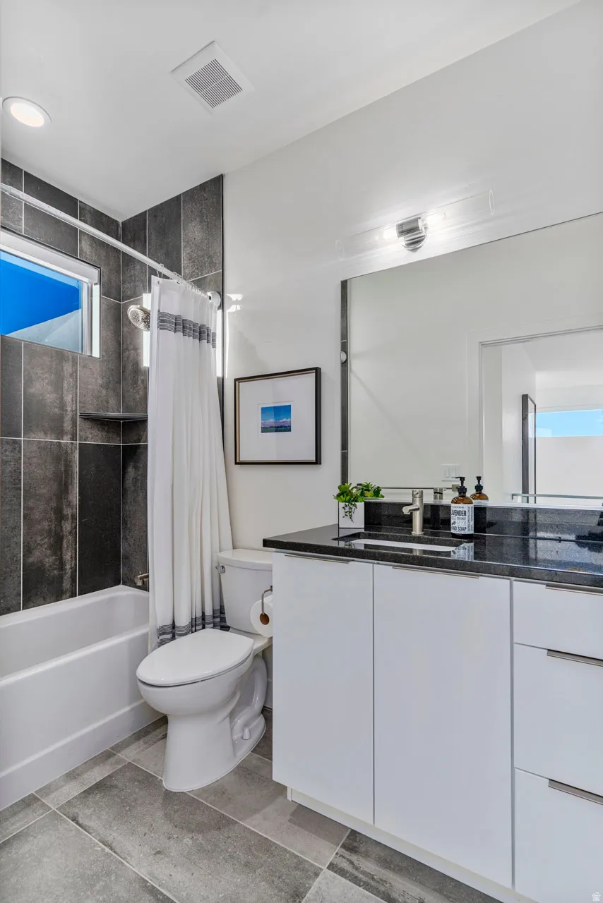 Full bathroom featuring a white vanity with black countertop, rectangular sink, and chrome faucet