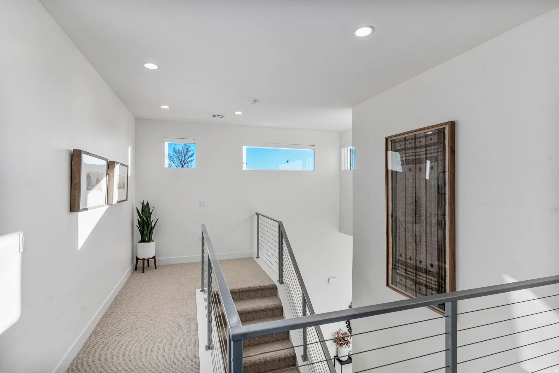Staircase featuring modern metal railings, carpeted treads, and recessed lighting