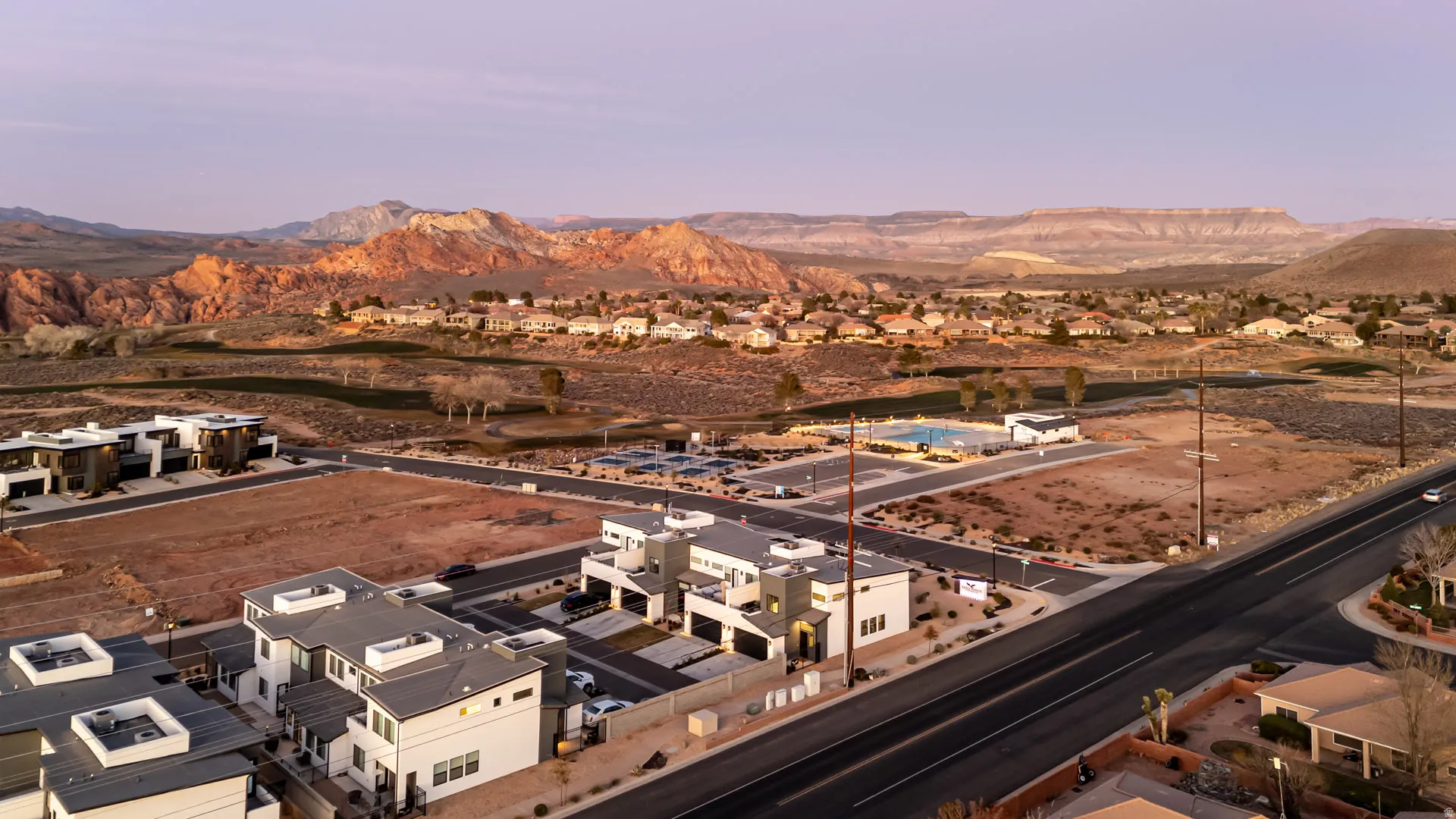 Contemporary residential architecture with flat roofs, a community pool, and distant red rock formations