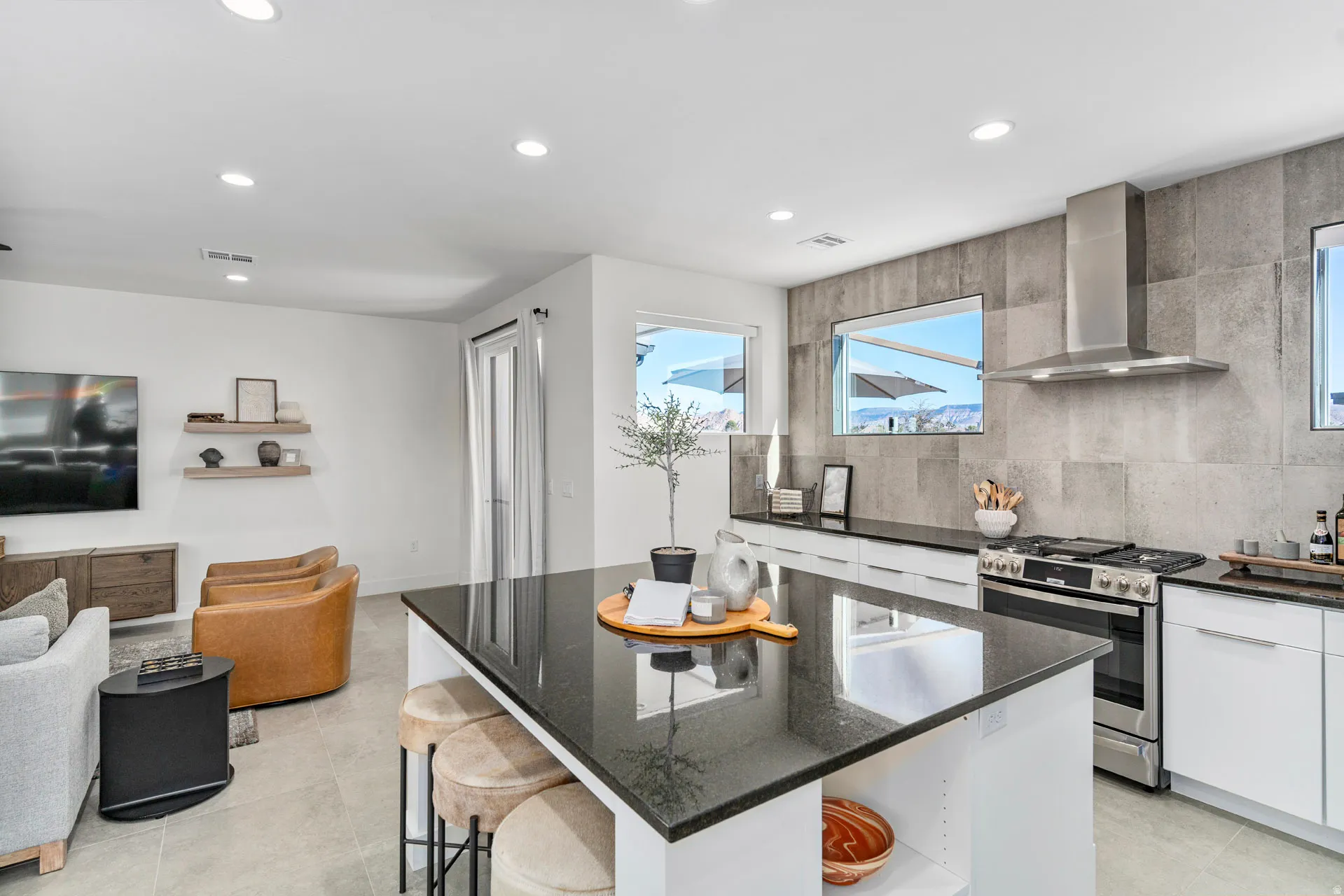Contemporary kitchen featuring a large central island with a dark countertop, stainless steel appliances, a tile backsplash, and recessed lighting