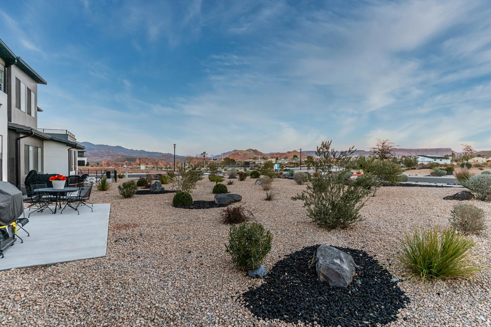 Expansive outdoor space featuring a concrete patio, low-maintenance gravel landscaping, and mature desert plantings