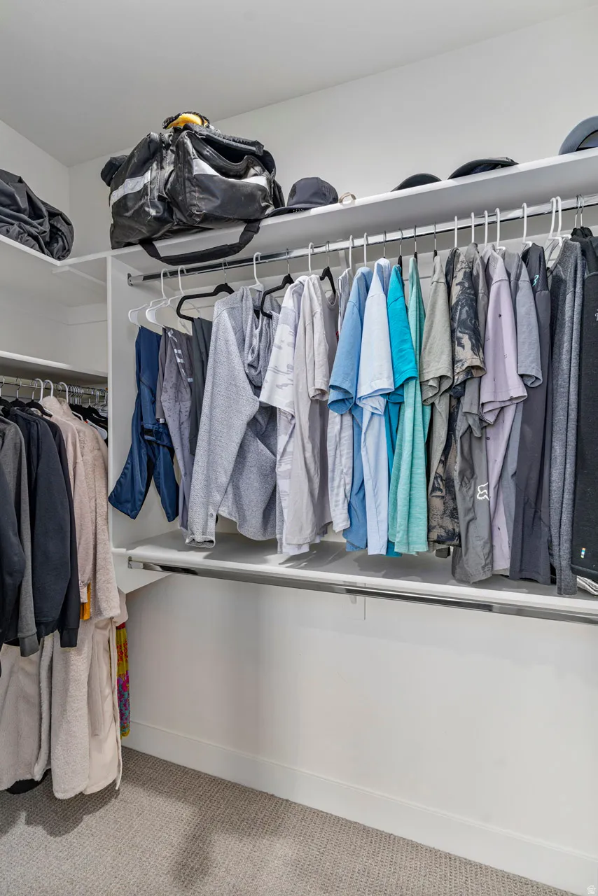 Primary bedroom organized closet system featuring multiple hanging rods and integrated shelving