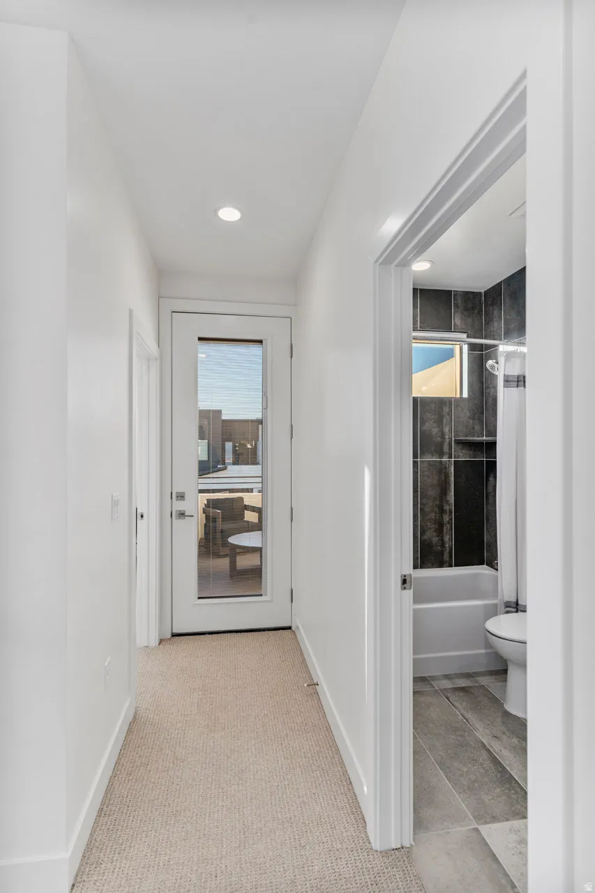 Hallway featuring recessed lighting, light-toned carpet, and a full-light door providing outdoor access to front porch.