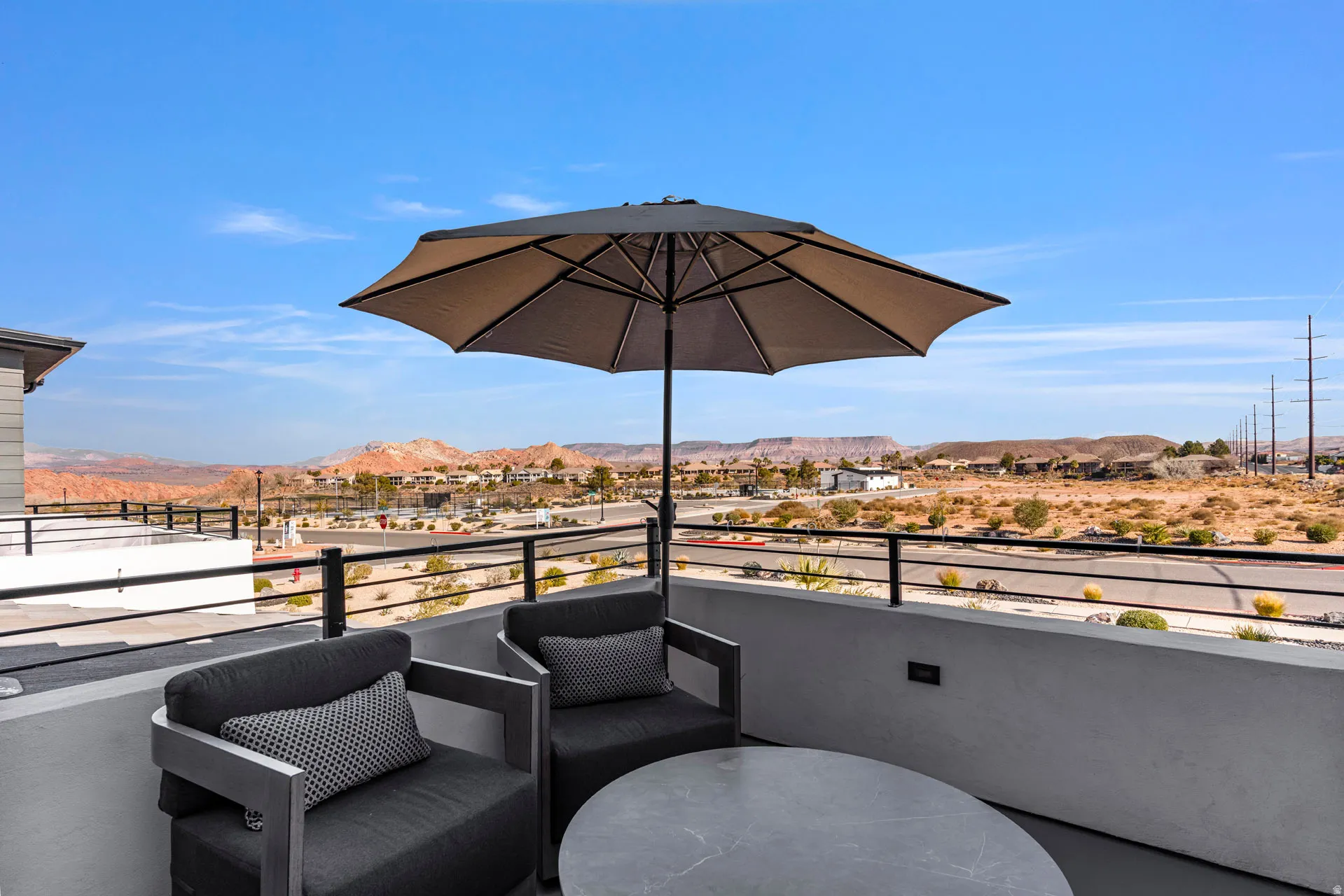 Primary bedroom expansive outdoor balcony featuring a dark metal railing, concrete half-wall, and clear desert scenery with distant mountains