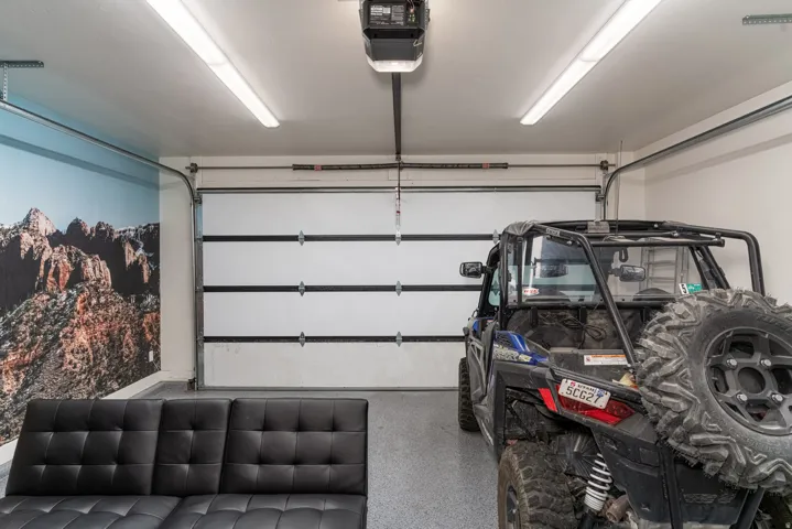 Garage space featuring a single overhead door, epoxy coated flooring, and track lighting