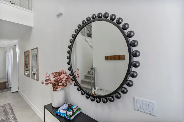 Entryway featuring a large circular mirror with a decorative studded frame, a console table, and two framed wall art pieces