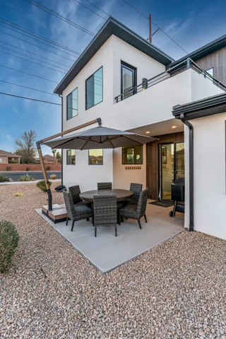 Modern two-story exterior featuring white stucco, dark trim, and a second-story balcony with metal railing