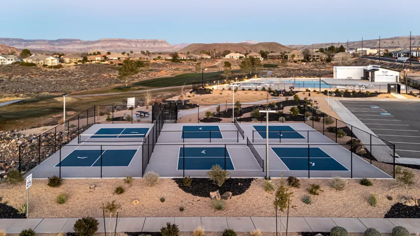 Fenced pickleball courts featuring blue and gray playing surfaces