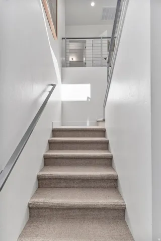 Upgraded carpeted staircase with contemporary metal handrails