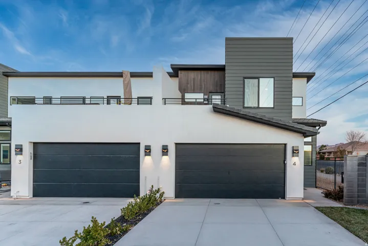 Contemporary facade featuring white stucco, dark gray siding, and natural wood-tone accents
