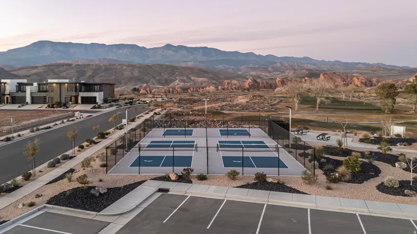 Four pickleball courts with perimeter fencing, surrounded by desert landscaping and framed by distant mountains