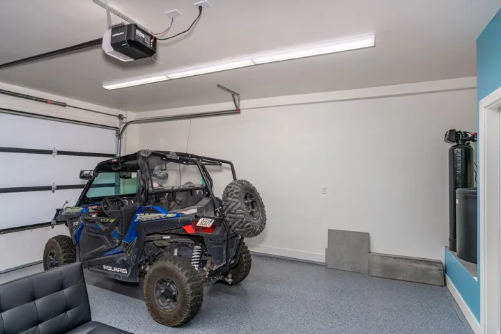 Spacious garage featuring a durable epoxy-coated floor, bright overhead lighting, and an automatic garage door opener