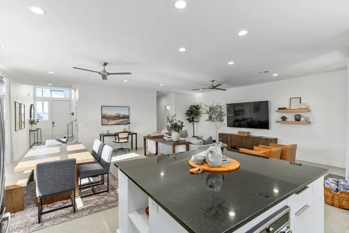 Open-concept living space featuring a dark stone-finish island with integrated oven, recessed lighting throughout, and a ceiling fan