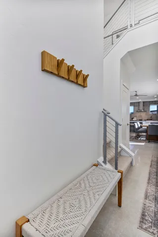 Open-concept entryway featuring a modern staircase with cable railings, expansive tile flooring, and a clear sightline into the kitchen with stainless steel appliances
