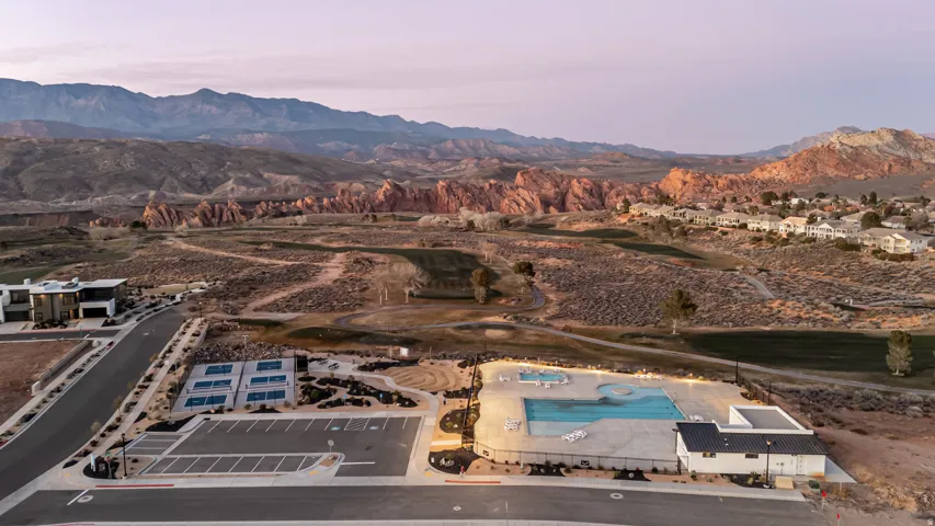 Community amenities featuring an illuminated swimming pool, pickleball courts, and a spacious parking area