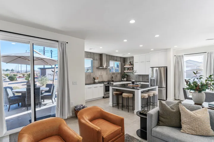 Modern kitchen featuring white cabinetry, stainless steel appliances, a black countertop island with seating, and a full-height tile backsplash