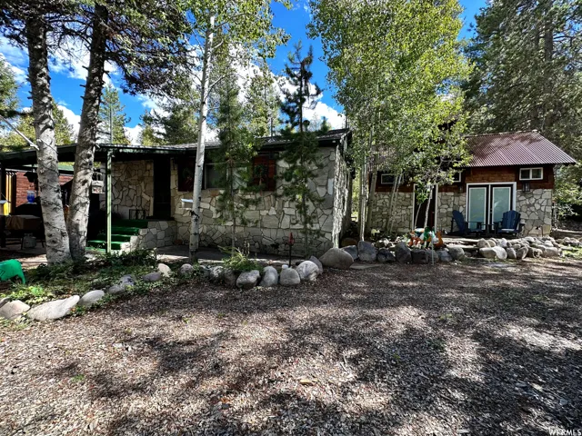 Stone-sided cabin featuring a covered entry and a separate stone-sided guest house with a metal roof and double patio doors