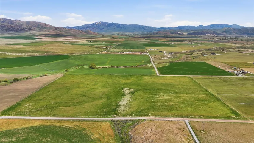 Expansive agricultural parcels with cultivated fields, unpaved roads, and distant mountain ranges under a clear sky