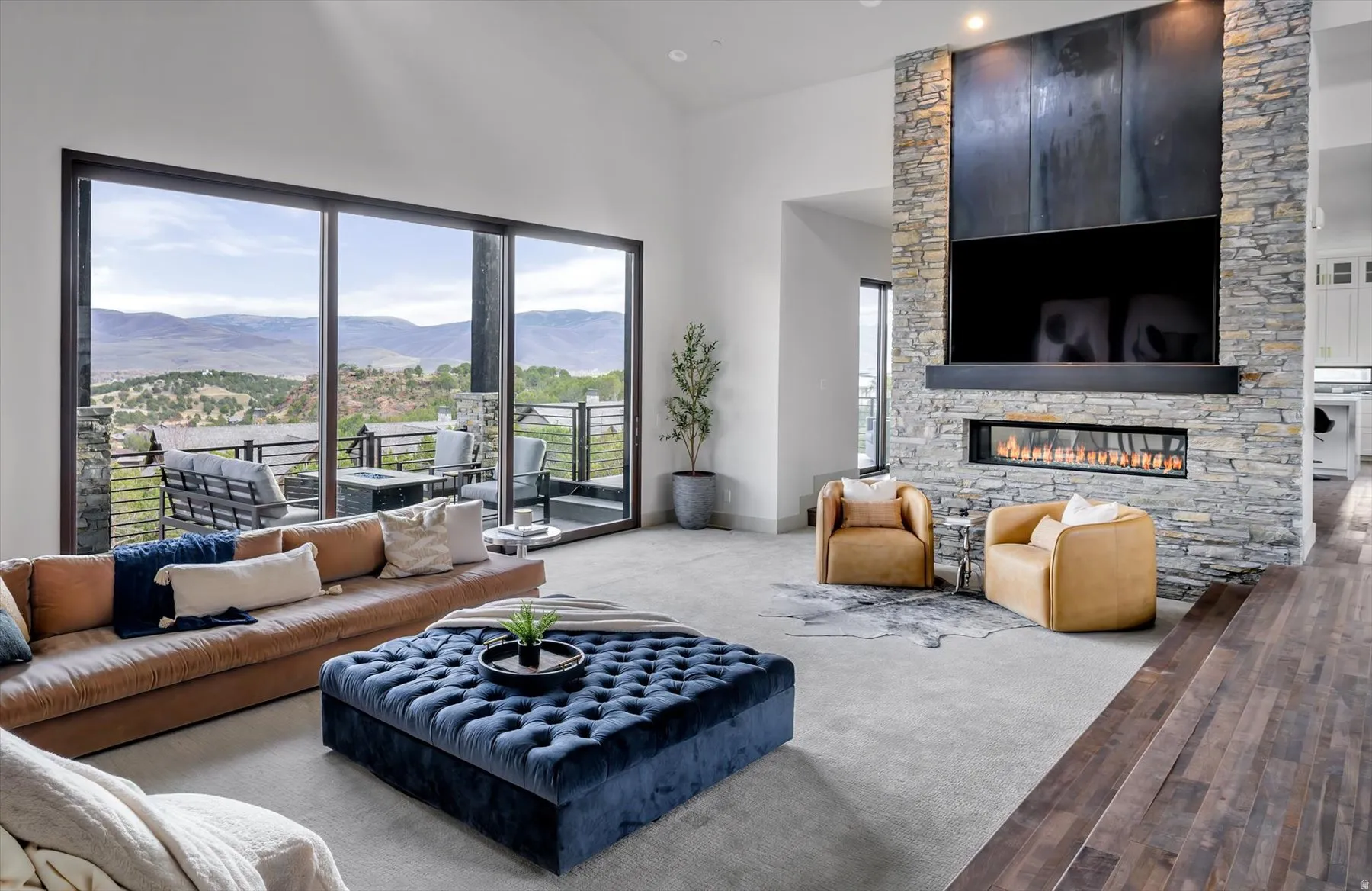 Spacious living area featuring expansive glass sliding doors, a gas fireplace with a stone surround, and high ceilings
