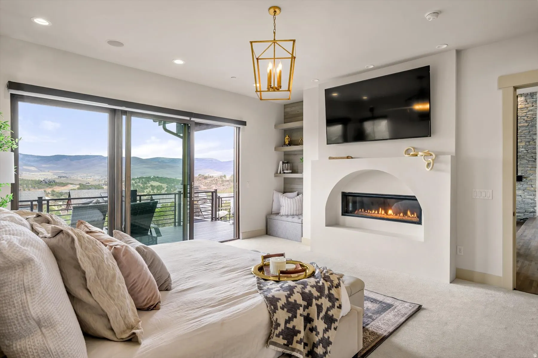 Spacious master interior featuring expansive sliding glass doors opening to an outdoor deck, an updated fireplace.