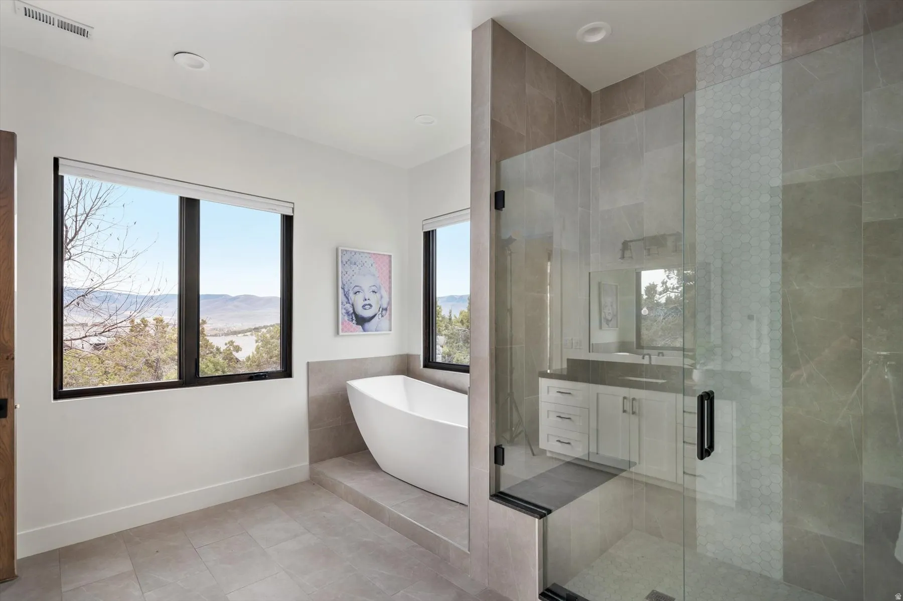 Spacious bathroom featuring a freestanding soaking tub, a glass-enclosed shower with custom tile.
