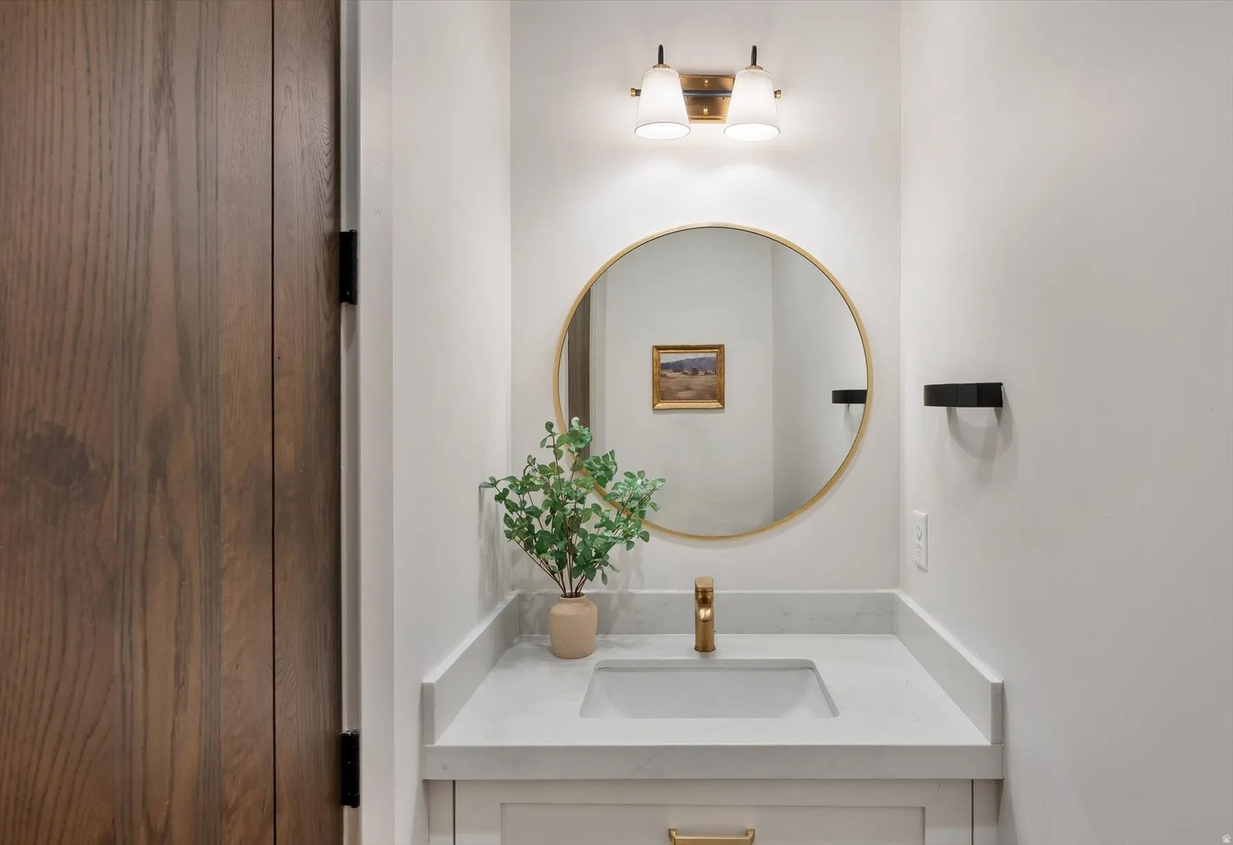 Bathroom vanity featuring a quartz countertop, integrated sink, and brass-finish faucet
