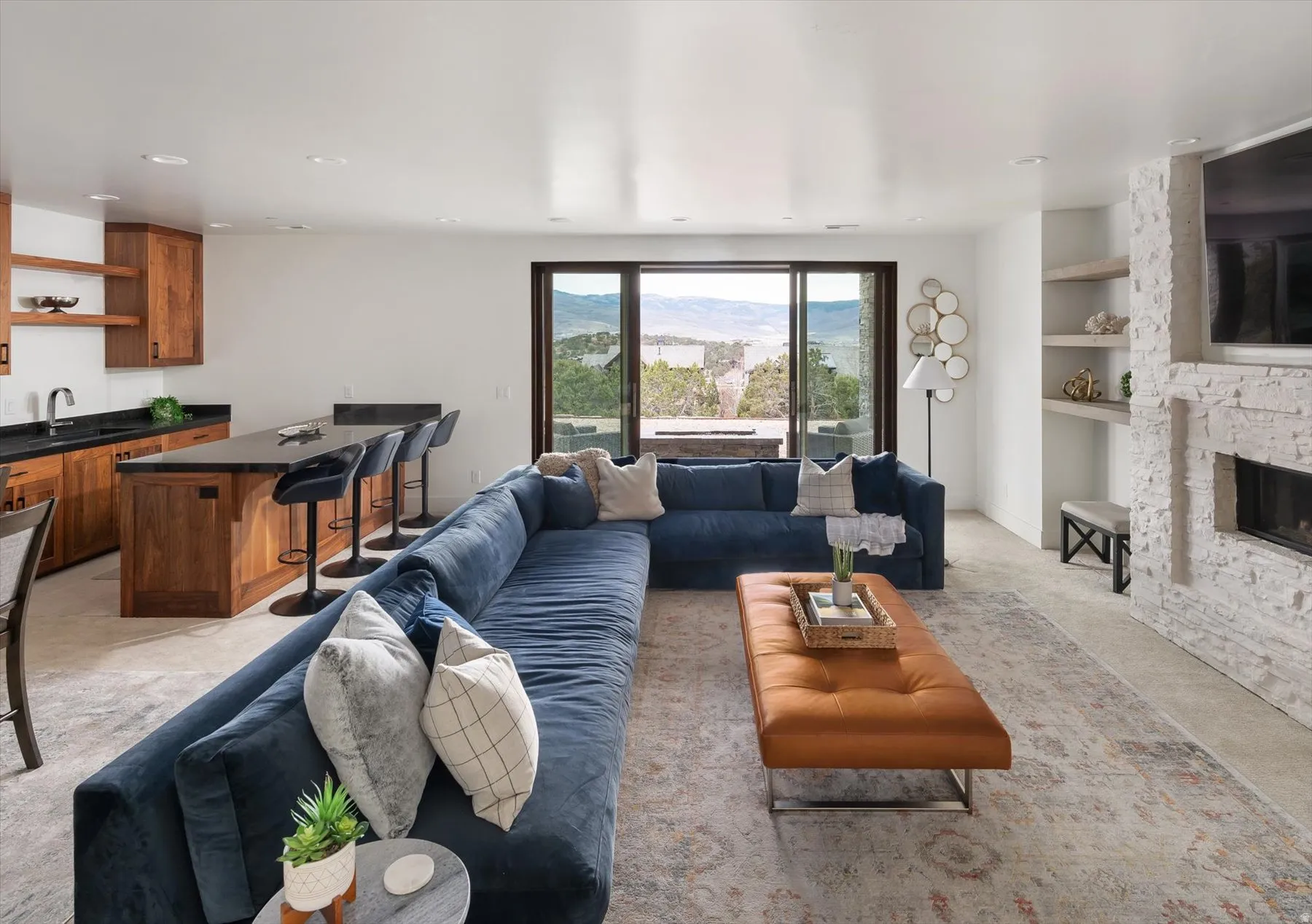 Open-concept living area featuring an updated stone fireplace, integrated shelving, and a wet bar.