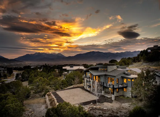 Contemporary-style residence with a dark gray exterior, stone accents, multiple balconies, and abundant windows
