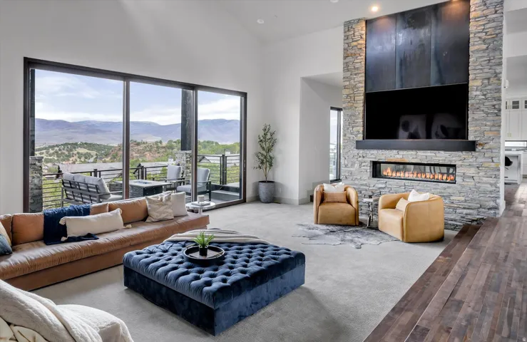 Spacious living area featuring expansive glass sliding doors, a gas fireplace with a stone surround, and high ceilings