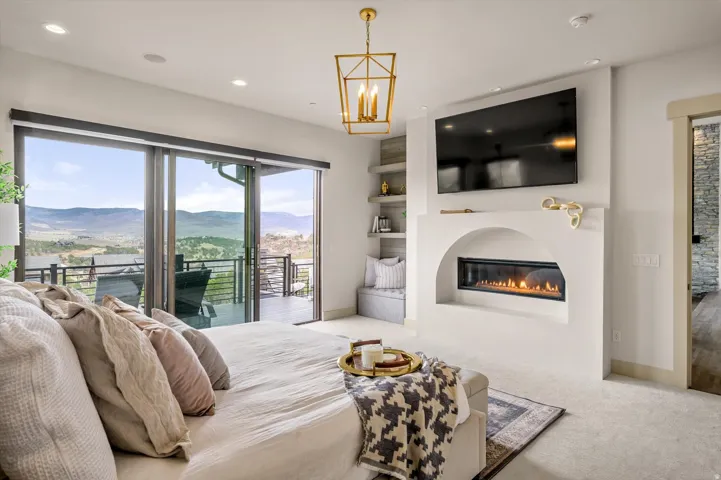 Spacious master interior featuring expansive sliding glass doors opening to an outdoor deck, an updated fireplace.