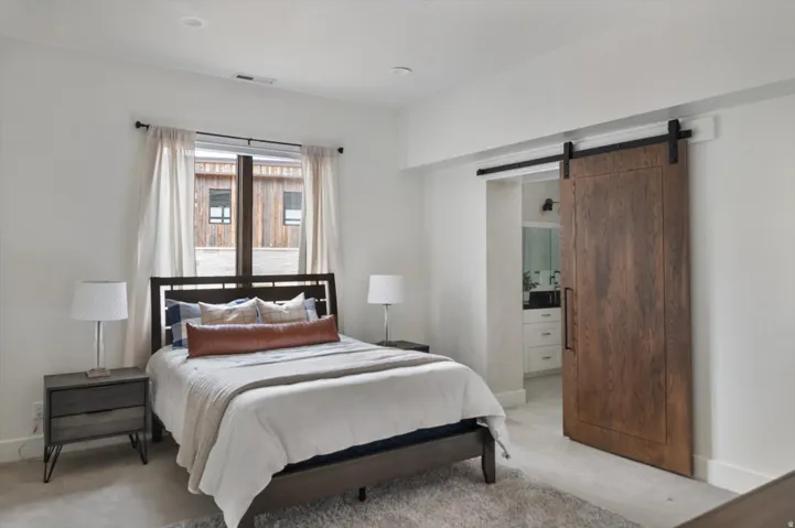Bedroom with a natural wood barn door, recessed lighting.