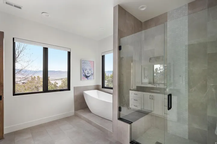 Spacious bathroom featuring a freestanding soaking tub, a glass-enclosed shower with custom tile.