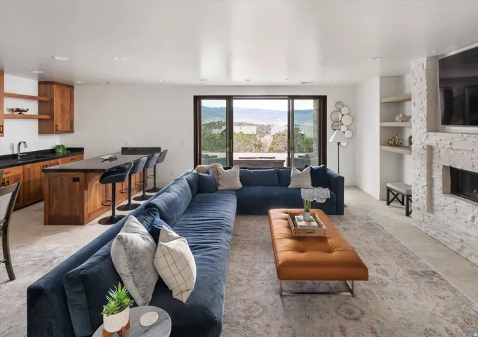 Open-concept living area featuring an updated stone fireplace, integrated shelving, and a wet bar.