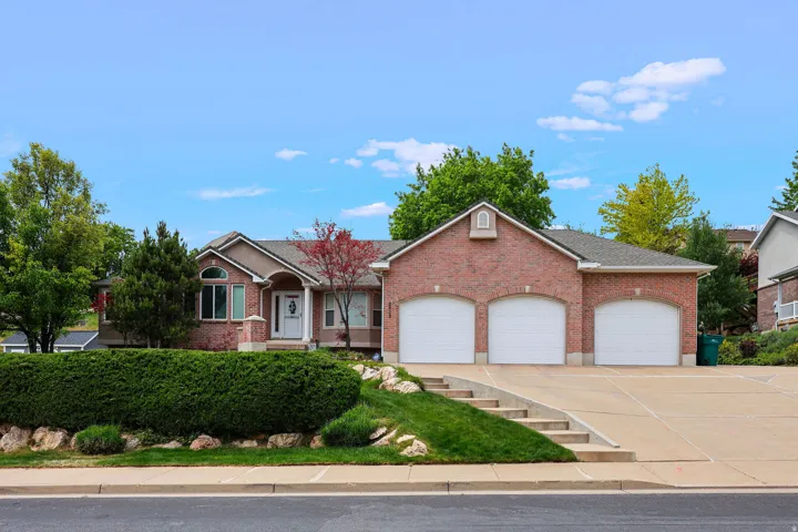 Brick exterior featuring a three-car garage, concrete driveway, and front entryway with a decorative glass door