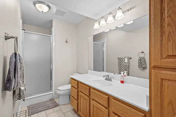 Bathroom vanity featuring wood cabinetry, white countertop, and an integrated sink with a chrome faucet