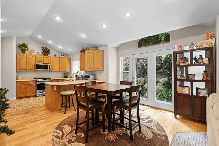 Kitchen and dining area featuring vaulted ceilings with recessed lighting, wood-finish flooring, and a kitchen island with seating